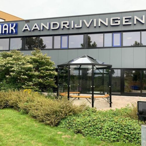 Meetingpoint - rokersoverkapping Paris 37 Moderne rookoverkapping met glazen wanden en dak en zitbanken geleverd en gemonteerd bij MAK aandrijvingen